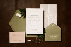 the wedding stationery is laid out on top of the brown tablecloth and it's contents include a pair of scissors