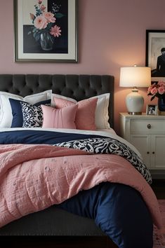 a bed with pink and blue comforters in a bedroom next to a painting on the wall