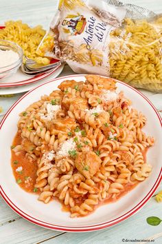 a plate of pasta with sauce and parmesan cheese on the side next to a bowl of macaroni and cheese