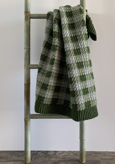 a green and white checkered blanket hanging on a ladder