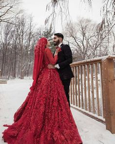 a man and woman dressed in red standing on a bridge