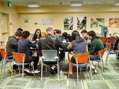 a group of people sitting around a table with laptops