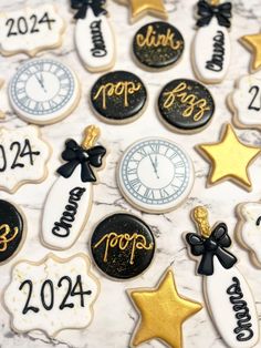 decorated cookies with black and gold decorations on a marble surface, which reads happy new year