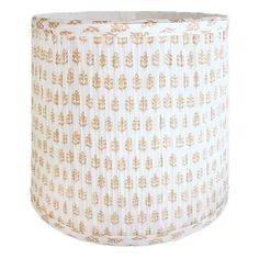 a lamp shade that is white and gold with leaves on the bottom, in front of a