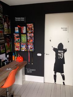 a room with black walls and white flooring has an image of a soccer player painted on the door