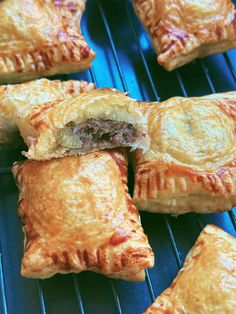 several pastries sitting on top of a metal rack next to each other, with meat in the middle