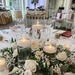 white flowers and candles are on the centerpiece in this wedding reception table set up