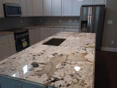 a kitchen with white cabinets and granite counter tops