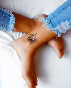 a woman's foot with a tattoo on her left leg and the sun in the background