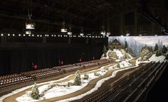 a model train set is on display in a dark room with lights hanging from the ceiling