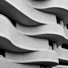 a black and white photo of a building with wavy lines on the outside, looking like it is made out of bricks