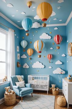 a baby's room decorated in blue and white with hot air balloons on the wall