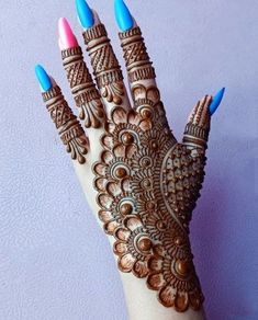 a woman's hand with blue and pink nail polishes on her hands, decorated with hendi