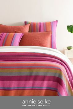 a bed with pink, orange and green striped bedspread