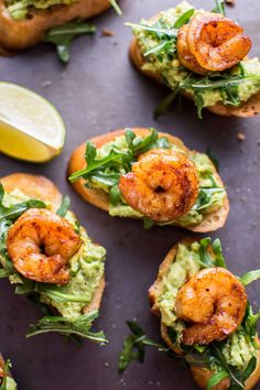 shrimp and guacamole on toasted bread with lime wedges next to it