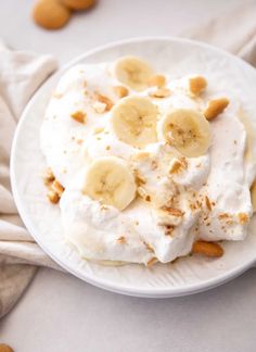 a white plate topped with whipped cream and banana slices on top of almonds next to cookies