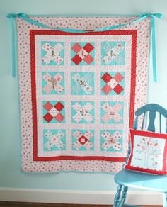 a chair next to a quilt hanging on the wall