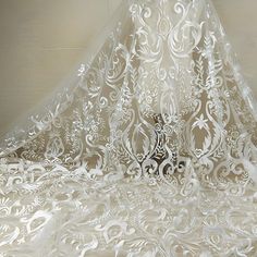 an intricately designed veil is hanging from the ceiling in front of a white wall