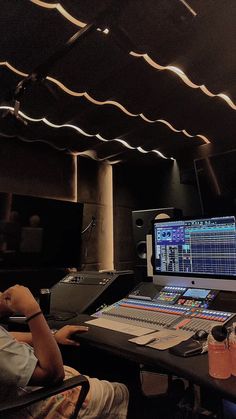 a man sitting at a desk in front of a computer monitor and sound mixing equipment