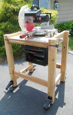 a table sawing on top of a wooden workbench in front of a house