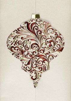 a christmas ornament hanging from the side of a white wall with red swirls