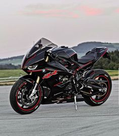 a black and red motorcycle parked on top of a parking lot next to a field