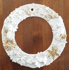 a white christmas wreath with gold stars and snowflakes hanging on a wooden table