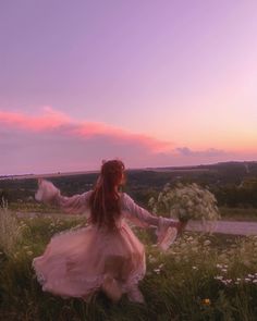 a woman is sitting in the grass with her arms spread out and she is wearing a white dress