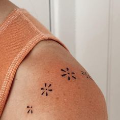 the back of a woman's shoulder with small black flowers on her left arm