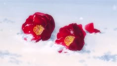 two red flowers that are in the snow