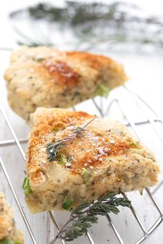 three pieces of food sitting on top of a metal rack next to each other and sprinkled with herbs