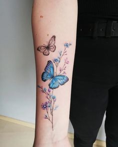 a blue butterfly and flower tattoo on the arm