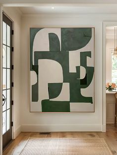 an abstract painting hangs on the wall in a room with wood floors and white walls