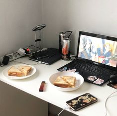 a laptop computer sitting on top of a desk next to a plate of food and drink