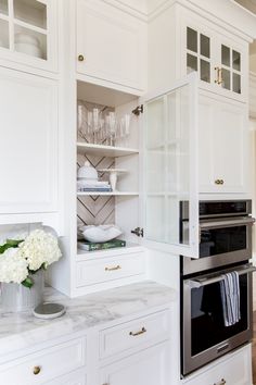 a kitchen with white cabinets and marble counter tops, an oven in the center is built into the wall