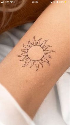 a woman's arm with a small sun tattoo on the left side of her arm