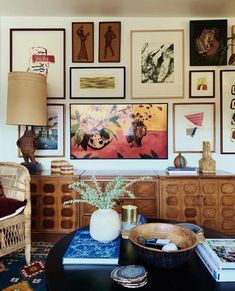 a living room filled with lots of pictures on the wall above a black coffee table