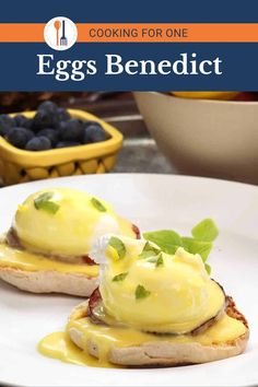 an egg benedict is on a white plate with blueberries and green leaves in the background