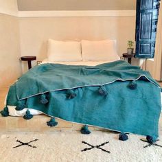 a bed with blue covers and pom poms on the bottom, in a bedroom