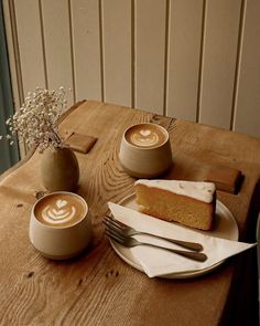 there is a piece of cake on the table with two cups of coffee next to it