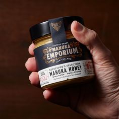 a hand holding a jar of manuka honey