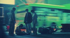 three men standing in front of a green bus