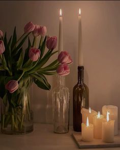 candles and vases with tulips in them on a white countertop next to bottles