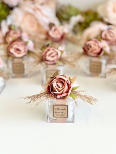 several small vases filled with pink flowers on top of a white table covered in burlap