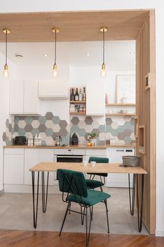 a kitchen with white cabinets and green chairs next to a wooden table in the middle