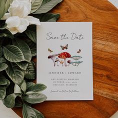 save the date card on top of a wooden plate with flowers and leaves around it