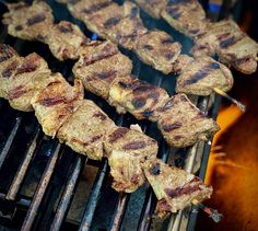 several skewers of meat cooking on a grill