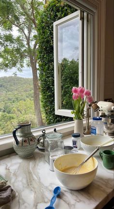 a kitchen counter with bowls and utensils on top of it next to a window