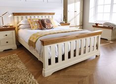 a white bed sitting on top of a hard wood floor next to two nightstands