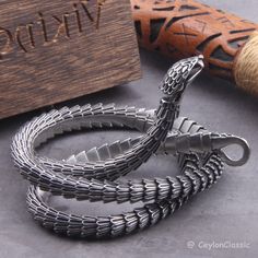 Elevate your style with this Viking Ouroboros vintage snake bracelet, a symbol of eternal cycles and timeless fashion. Crafted from high-quality stainless steel, this necklace exudes durability and style. Choose from three lengths: 50cm, 60cm, or 70cm, or opt for private custom sizing for the perfect fit. Packaged with care, each necklace comes with a black jewelry bag and a wooden box, making it an ideal gift for the fashion-forward individual in your life. Embrace the spirit of Viking heritage Engraved Metal Snake-shaped Jewelry, Snake-shaped Metal Bracelets As Gifts, Silver Metal Snake Bracelets, Silver Metal Snake Bracelet, Silver Snake-shaped Bracelet As Gift, Silver Snake-shaped Bracelet For Gift, Silver Snake-shaped Bracelets For Gifts, Vintage Snake-shaped Jewelry Gift, Vintage Snake Jewelry For Gifts